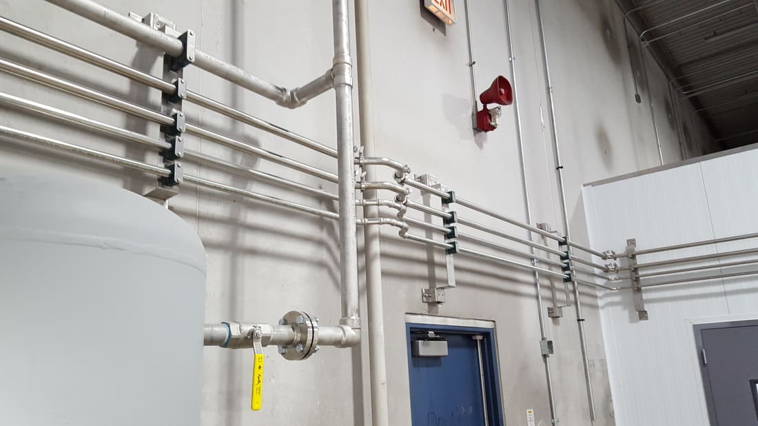 Stainless process piping runs on a plant wall